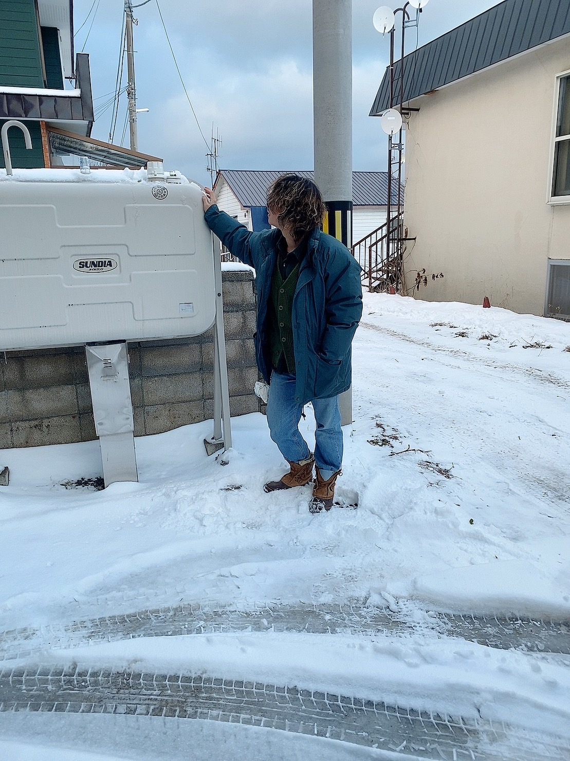 雪の積もった訪問先で、ホームタンクの設置状況を確認する様子